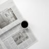 A fresh cup of coffee resting on a newspaper, perfect morning routine setup.